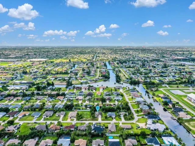 Aerial view of property and surrounding area featuring nearby suburban area and a nearby body of water
