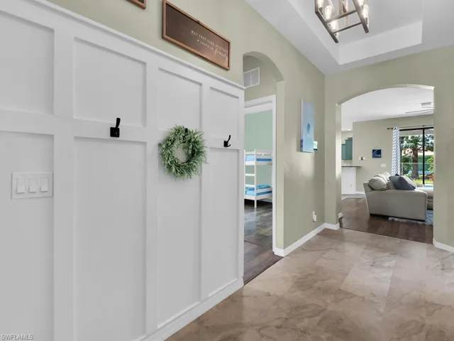 Mudroom featuring arched walkways, marble finish floors, and a chandelier