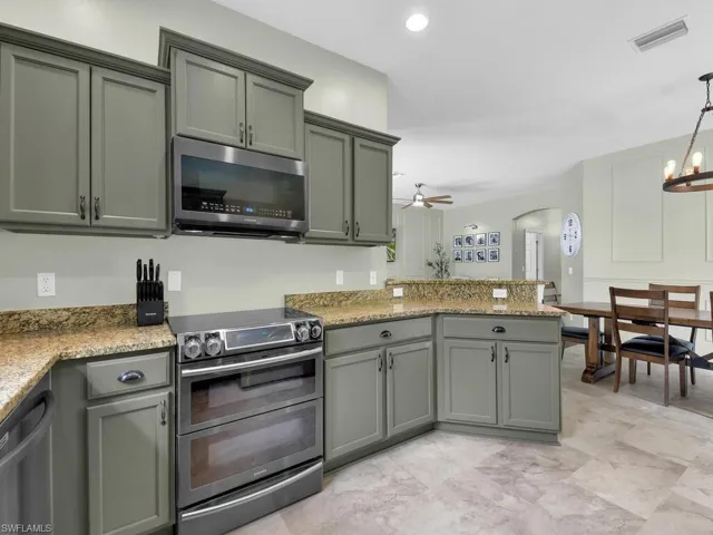 Kitchen with stainless steel appliances, a peninsula, arched walkways, a ceiling fan, and decorative light fixtures
