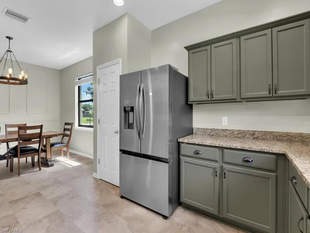 Kitchen with stainless steel fridge with ice dispenser, a chandelier, hanging light fixtures, and green cabinets