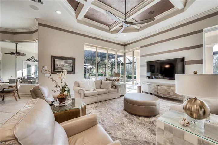 Living room with coffered ceiling, crown molding, a towering ceiling, ceiling fan, and beam ceiling