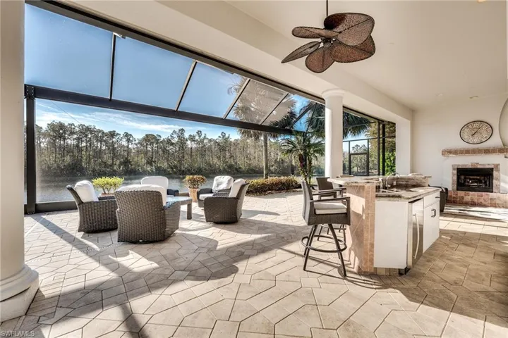 View of patio with ceiling fan, an outdoor living space with a fireplace, and a wet bar