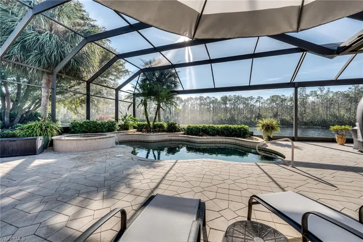 View of swimming pool with an in ground hot tub, a water view, a lanai, and a patio