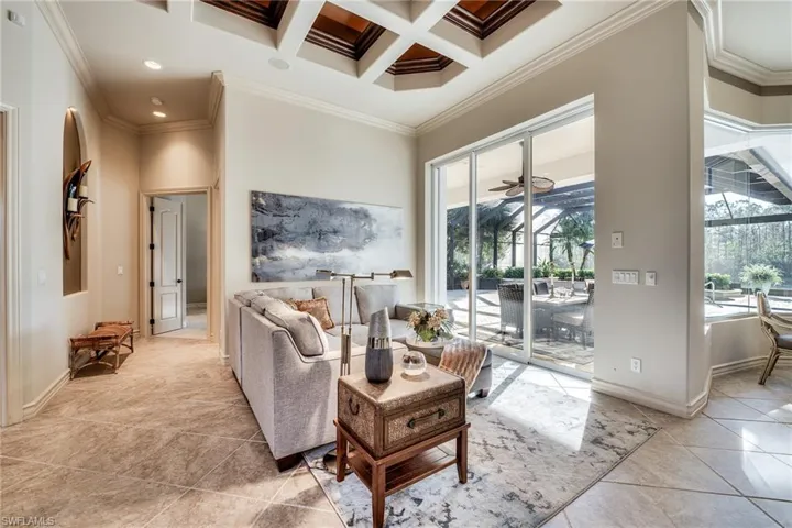 Tiled living room featuring beamed ceiling, a towering ceiling, ornamental molding, and coffered ceiling