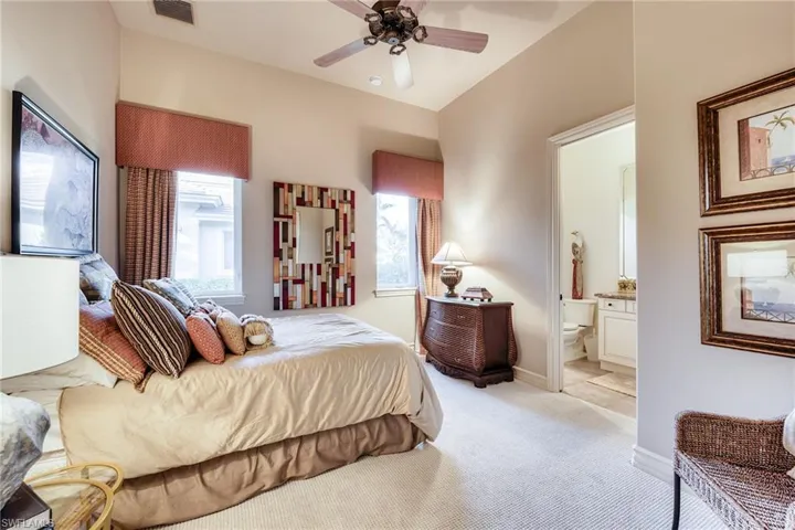 Carpeted bedroom with ensuite bath and ceiling fan