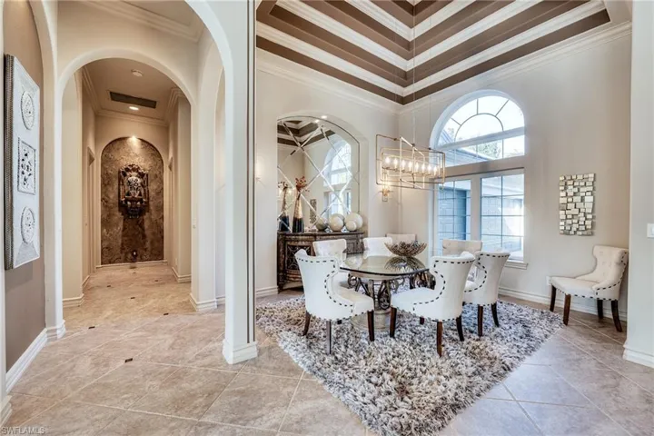 Dining space featuring light tile patterned floors, crown molding, and a notable chandelier