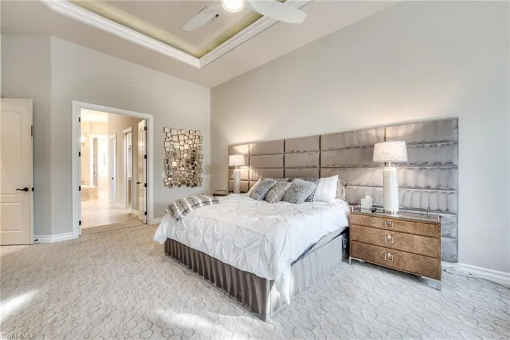 Bedroom featuring crown molding, connected bathroom, light colored carpet, and a tray ceiling