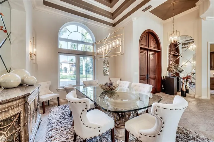 Dining area featuring a towering ceiling, ornamental molding, plenty of natural light, and a notable chandelier