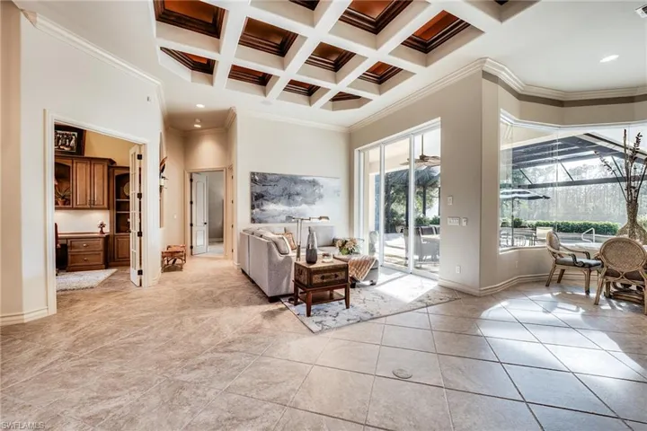 Tiled living room featuring a high ceiling, ornamental molding, coffered ceiling, and beamed ceiling