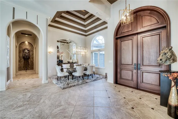 Tiled entryway featuring ornamental molding and a notable chandelier