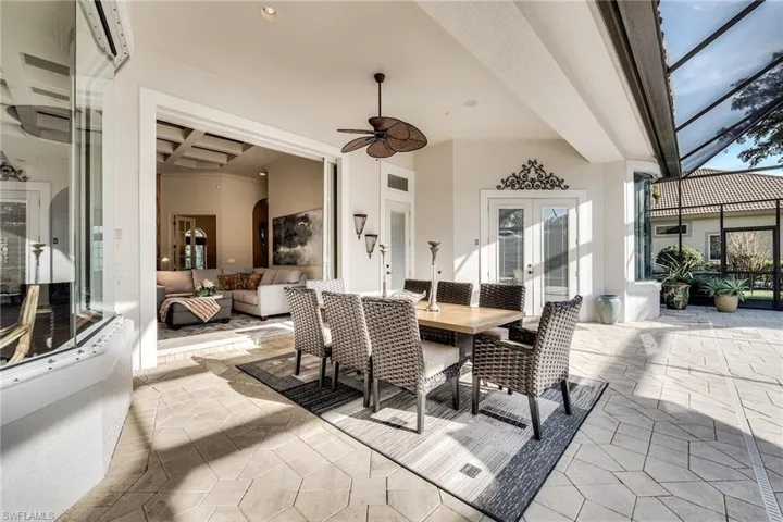 View of patio with a wall mounted AC, french doors, ceiling fan, and glass enclosure