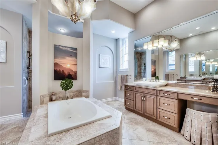 Bathroom with vanity, independent shower and bath, a healthy amount of sunlight, and an inviting chandelier
