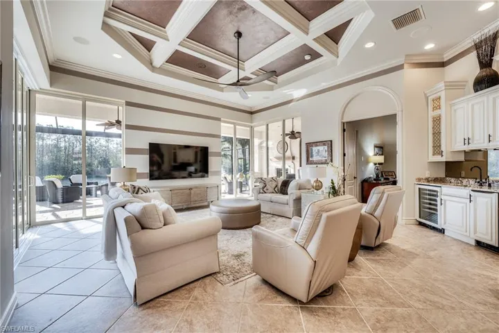 Tiled living room with a healthy amount of sunlight, beverage cooler, and ceiling fan