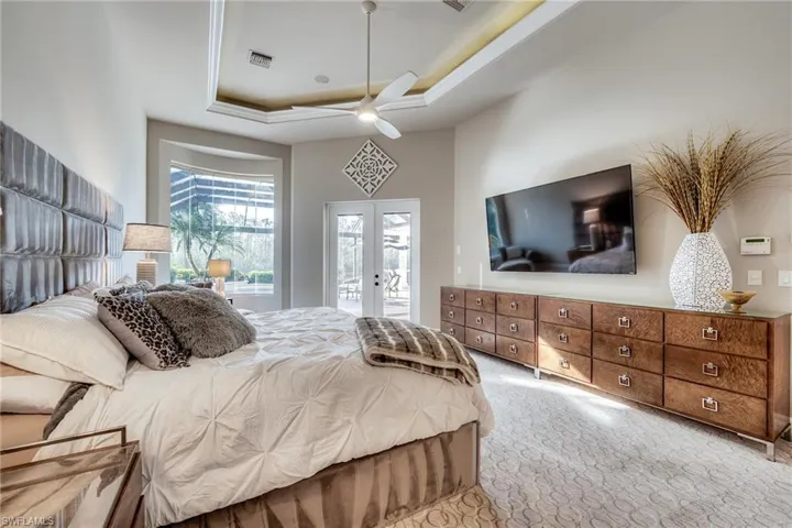 Carpeted bedroom with a tray ceiling, access to outside, french doors, and ceiling fan
