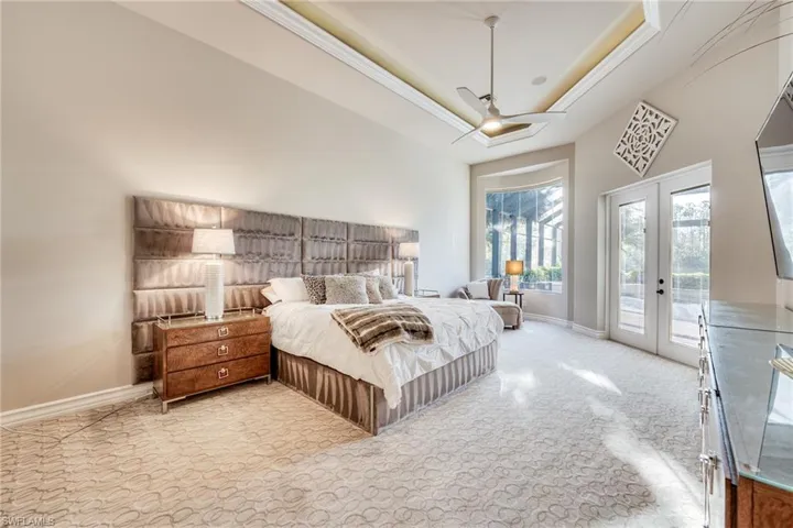 Carpeted bedroom featuring french doors, ceiling fan, a tray ceiling, and access to outside