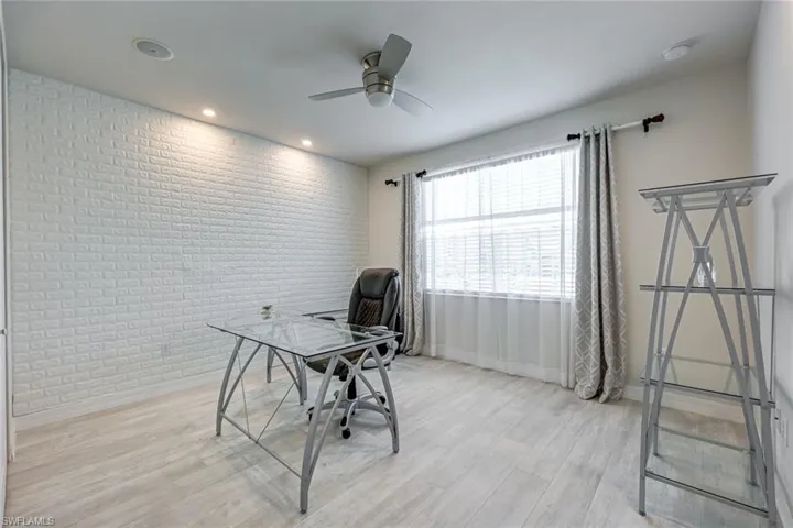 Office featuring brick wall, light wood finished floors, ceiling fan, and recessed lighting