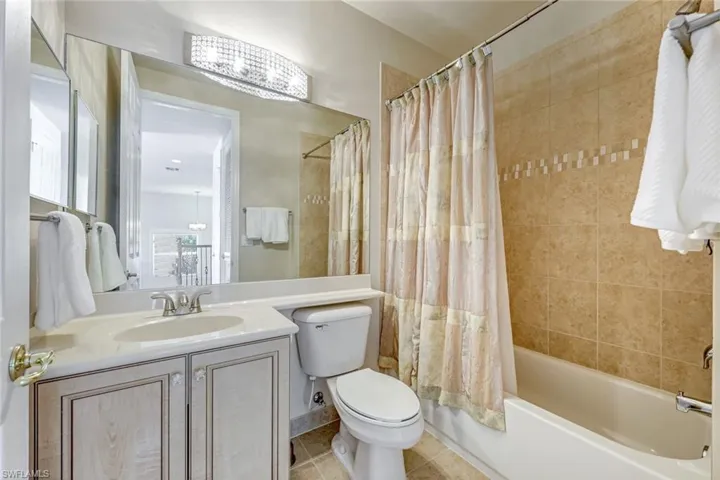 Bathroom with shower / bathtub combination with curtain, vanity, and light tile patterned floors