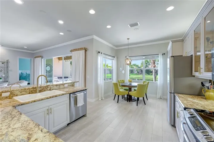 Kitchen featuring light stone counters, white cabinetry, appliances with stainless steel finishes, crown molding, and recessed lighting