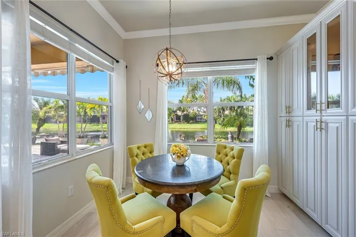 Dining area with light wood-style flooring, crown molding, and a chandelier