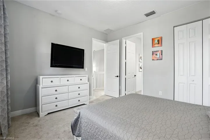 Bedroom with light carpet, a closet, and a textured ceiling
