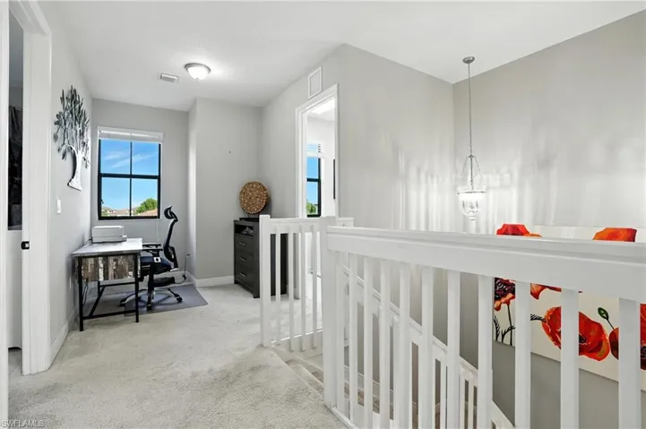 Hallway featuring a desk and light carpet