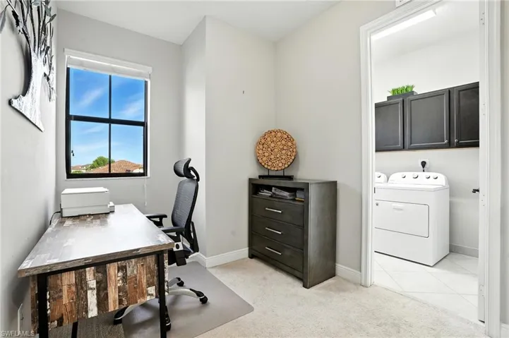 Home office with light carpet, separate washer and dryer, and light tile patterned floors