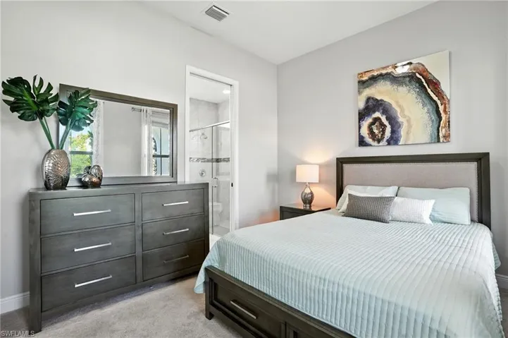 Bedroom with ensuite bath and light colored carpet