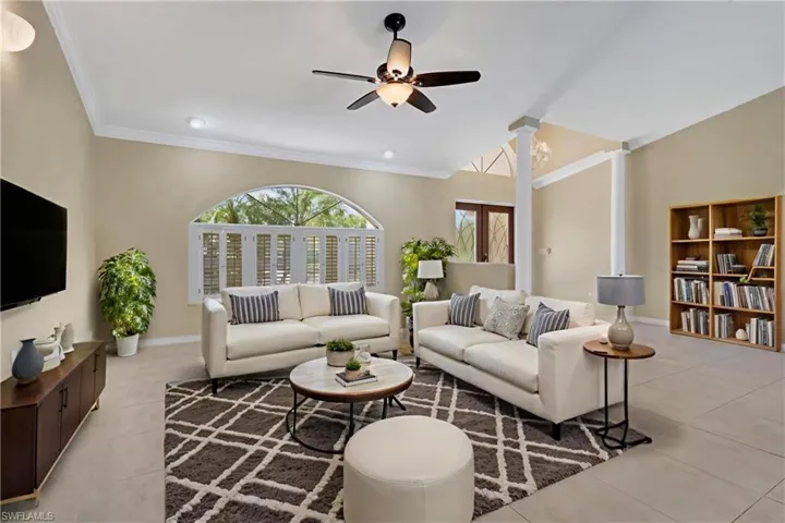 Living area with crown molding, a ceiling fan, decorative columns, and light tile patterned floors