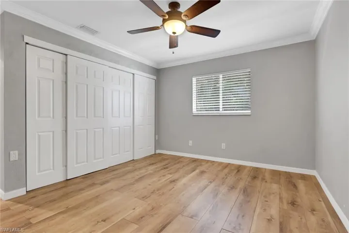 Unfurnished bedroom with ornamental molding, light wood finished floors, a ceiling fan, and a closet