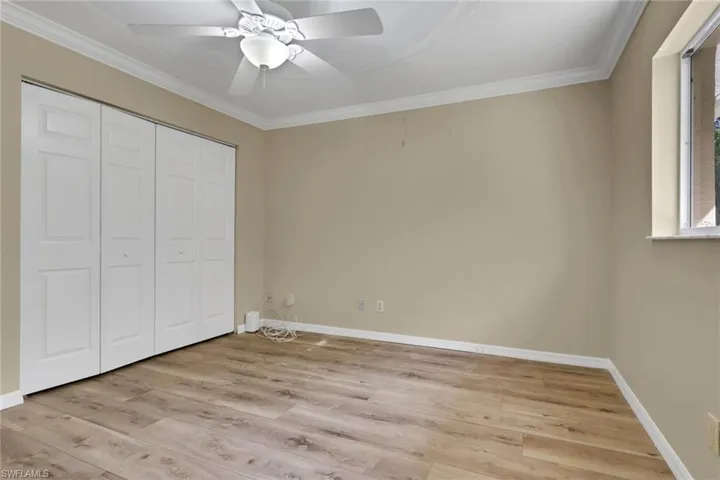 Unfurnished bedroom featuring light wood finished floors, ornamental molding, a closet, and a ceiling fan
