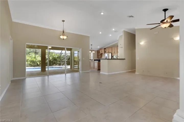Unfurnished living room featuring ornamental molding, light tile patterned floors, ceiling fan, vaulted ceiling, and recessed lighting