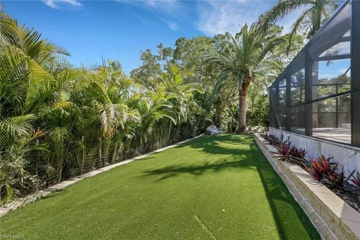View of green lawn featuring a sunroom and glass enclosure