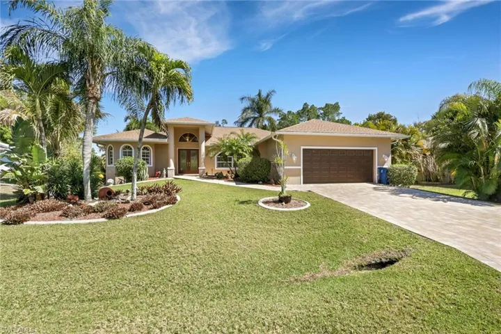 View of front of house featuring stucco siding, an attached garage, decorative driveway, french doors, and a front lawn