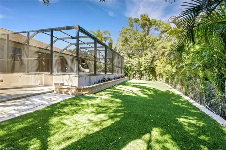 View of green lawn featuring a sunroom, glass enclosure, and a patio area