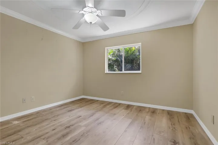 Empty room with light wood finished floors, ornamental molding, and a ceiling fan