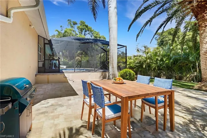 View of patio featuring a lanai, grilling area, outdoor dining space, an outdoor pool, and a sunroom