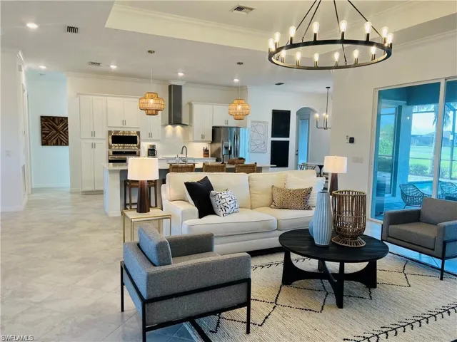 Tiled living room featuring a chandelier, a raised ceiling, and crown molding