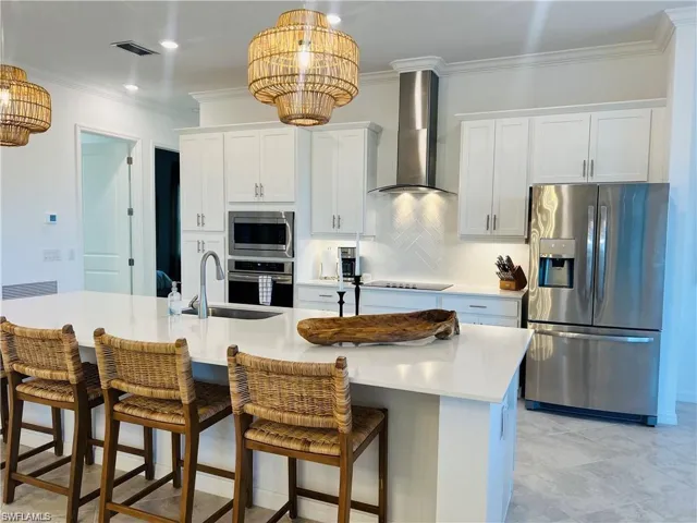 Kitchen featuring stainless steel appliances, sink, an island with sink, and wall chimney exhaust hood