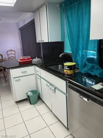 Kitchen with sink, white cabinets, dishwashing machine, and light tile floors