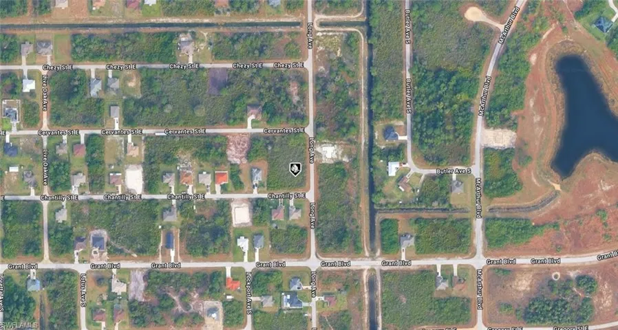 Satellite Imagery. Displaying a residential area with streets, structures, and undeveloped land parcels, including a body of water in the upper right quadrant