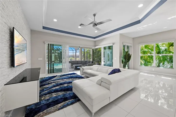 Living area featuring ceiling fan, recessed lighting, light tile patterned floors, and a raised ceiling