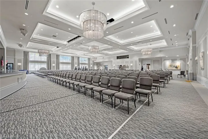 Cinema with coffered ceiling, crown molding, a chandelier, light carpet, and a decorative wall