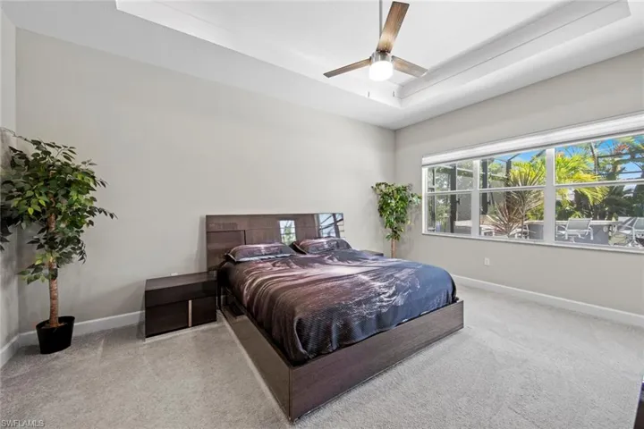 Bedroom featuring baseboards, carpet floors, ceiling fan, and a raised ceiling