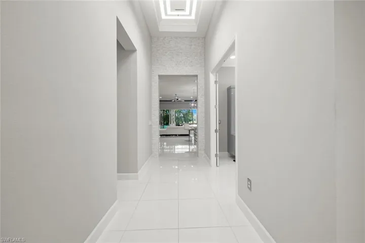 Hall with light tile patterned flooring and baseboards
