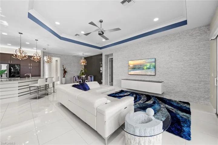 Living area with visible vents, ceiling fan with notable chandelier, and a raised ceiling