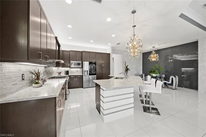 Kitchen featuring a notable chandelier, pendant lighting, tasteful backsplash, appliances with stainless steel finishes, and dark brown cabinets