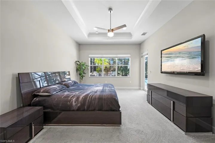 Bedroom featuring carpet floors, a ceiling fan, a raised ceiling, baseboards, and visible vents