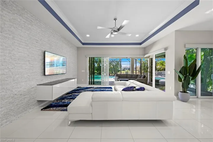 Bedroom with ceiling fan, tile patterned floors, recessed lighting, access to exterior, and a tray ceiling