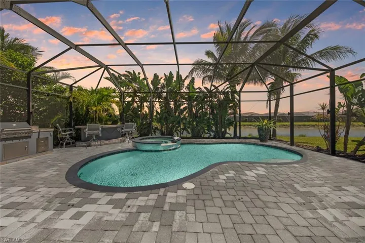 View of swimming pool featuring a lanai, a grill, a patio, a pool with connected hot tub, and area for grilling