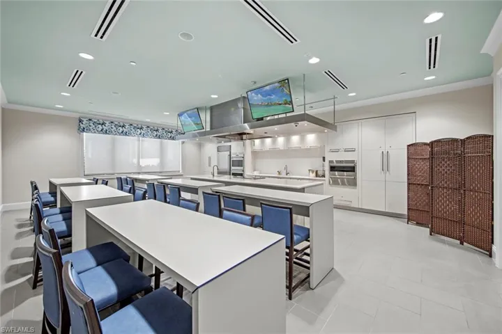 Kitchen with a large island with sink, light countertops, visible vents, white cabinets, and decorative backsplash